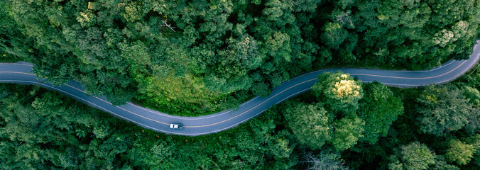 Aerial forest road with car creating abstract background for electric vehicle, ESG, sustainability and green investment business concepts.