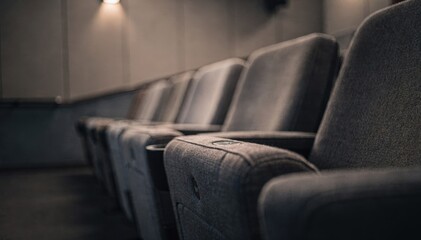 Closeup of minimalist decor details inside an indie theater during a quiet matinee with plush seats in sharp focus and ambient surroundings softly out of focus.