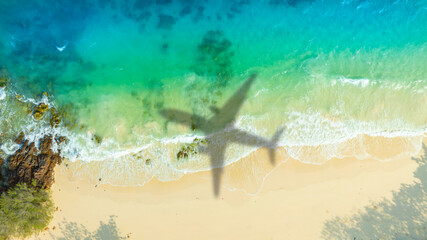 Aerial view of shadow passenger plane silhouette and sandy beach blue sea with waves at sea beach summer vacation sea travel concept 