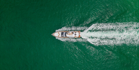 Top aerial view on motorboat. Motor boat yacht floating to marina. Motorboat tour by summer sea. Luxury yacht boat at sea. Summer vacation. Luxury yacht boat top view. Blue ocean.