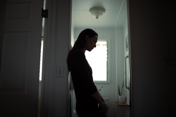 silhouette of tired woman leaning against wall in bathroom, stress and mental health concept 