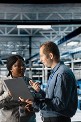 Server room coworkers troubleshooting server connectivity issues using software on notebook. Teamworking data center technicians upgrading enterprise networks hardware using laptop