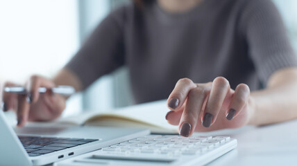 Close up woman using calculator to calculate home finance and writing note, accounting on table, budget management. budgeting and tax calculation