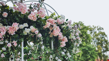 Pink and white roses and hydrangeas decorating a white metallic gazebo