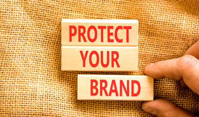 Protect your brand words symbol. Concept words Protect your brand on beautiful wooden blocks. Beautiful canvas background. Businessman hand. Business and protect your brand concept. Copy space.