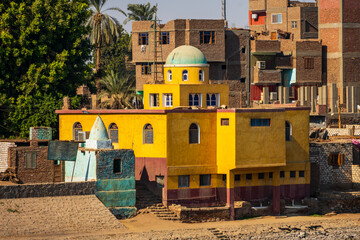 Colorful riverside building with dome and village houses