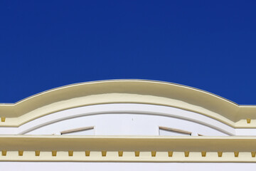 Elegant architectural detail with a curved classical facade against a clear deep blue sky, ideal for urban design, travel themes, and building exterior concepts.