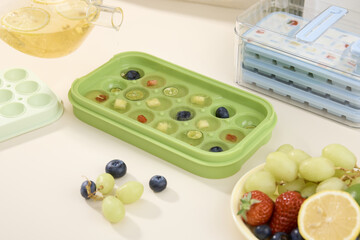 Fruit tea ice cubes with berries and grapes in silicone tray on kitchen counter