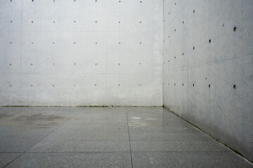 A minimalist space composed of concrete walls and tiled flooring with geometric lines and industrial texture