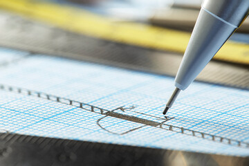 mechanical pencil makes a drawing on graph paper with ruler, dividers and tape measure. Construction and architectural industry.