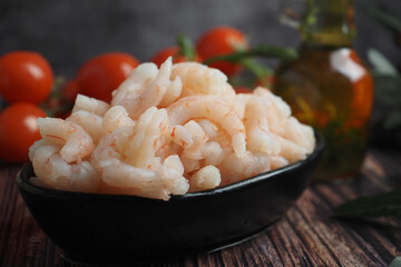 Fresh shrimp on a black plate with tomatoes and oil