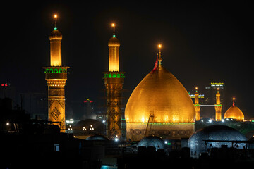 Karbala, Iraq - December 28, 2025: Golden dome and illuminated minarets of the Imam Hussain Shrine glowing at dusk in Karbala, Iraq