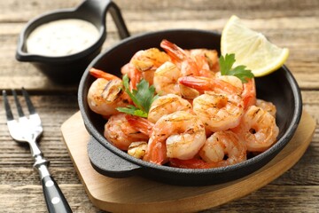 Tasty grilled shrimps served with sauce on wooden table, closeup