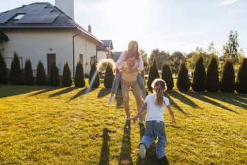 Happy family playing together in backyard with solar panels