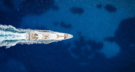 Aerial overhead view of a modern luxury yacht sailing over the blue ocean with copy space