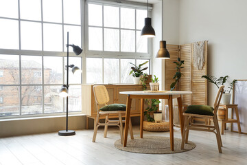 Interior of stylish dining room with table, houseplants, big window and glowing lamp