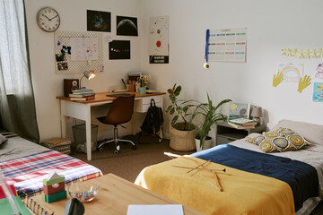 Wide angle shot of teenager bedroom with study desk, school supplies, calendar, posters, beds, showing student organization, youth lifestyle. For education, dorm, parenting, back to school marketing