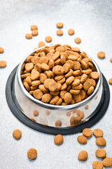 Dogs' food in metal a plate. Dry animal feed in a bowl close up. Dry food for puppies or dogs in a small bowl. Close up.