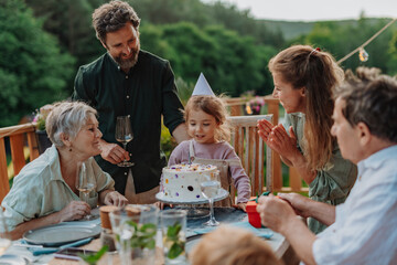 Multi generation family grilling outside on patio in summer during garden party