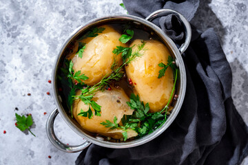 Cooked jacket potatoes with fresh herbs and peppercorns in pot