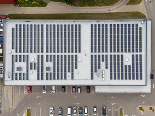 Aerial top-down view of large commercial building rooftop covered with solar panels, renewable energy and sustainable business infrastructure concept.