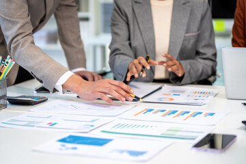 Business team reviewing financial charts and reports at a desk during a planning meeting, with laptop, calculator, pens and smartphone.