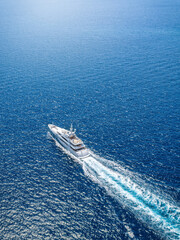 Aerial view of an ultra modern luxury yacht cruising over sparkling ocean with speed