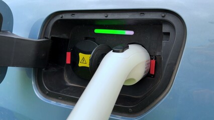 Charging port on electric vehicle with connected cable and colored indicator lights showing status
