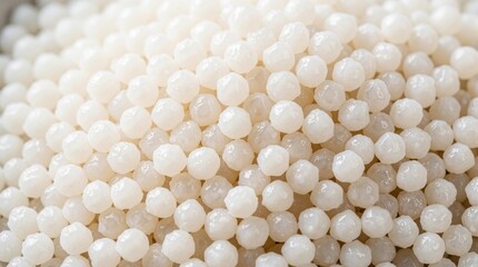 White tapioca pearls form a dense textured background. Small round starch balls create a sweet dessert ingredient close up, used in asian drinks.