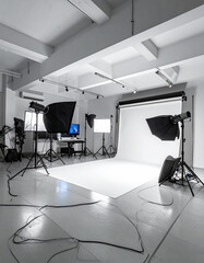 Professional photo studio with white backdrop and lighting equipment, no people.