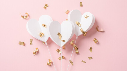 a festive arrangement of white heart-shaped balloons on a soft pink background, surrounded by golden confetti, perfect for celebrations and special occasions