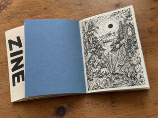 Open Zine Revealing an Intricate Nature Illustration on a Wooden Table